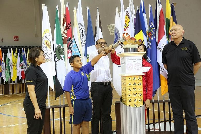 Minister of State for Education Dr Janil Puthucheary, with the help of Sembawang Primary School's Ricqiey Dannyall and Singapore Sports School's Crystal Wong (in red) lighting the NSG cauldron to mark the Games' opening.