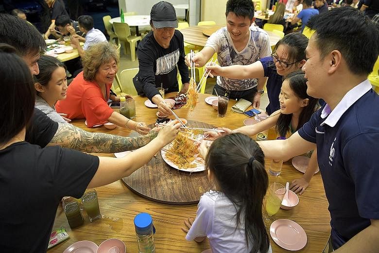 Logistics manager Mark Yee (far right) and his family having their reunion dinner at Uncle Leong Seafood in Lorong 8 Toa Payoh last night. He said they chose to have the traditional dinner early as the zi char restaurant is less crowded, and his fami