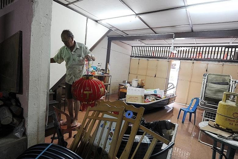 Mr Lam Jie, 67, standing on a chair to avoid the flood waters in his house in Sungai Lembing, Kuantan, yesterday. His plans for Chinese New Year have been disrupted after flood waters rose to waist-level, ruining many items in his residence. A priest