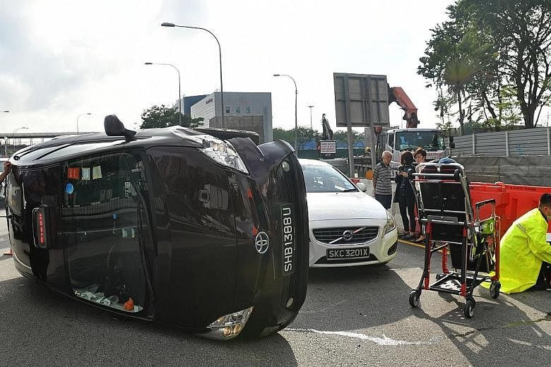 Top: The taxi driver standing by his vehicle, which was lying on its side after the accident in Braddell Road yesterday. Left: The taxi driver and a few others pushing the vehicle back onto its wheels in a joint effort.