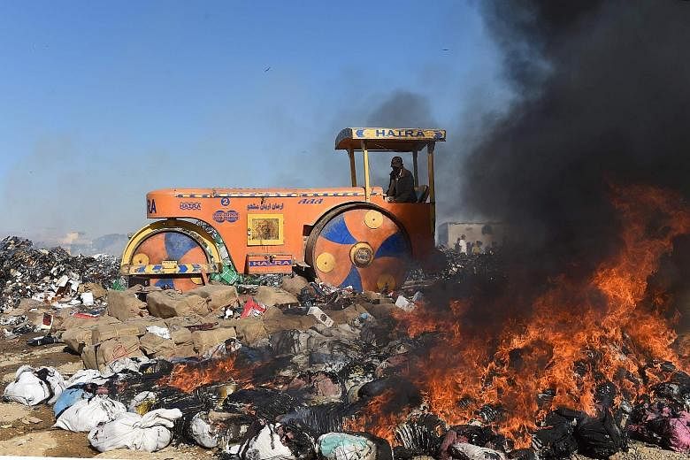 A Pakistani Customs official using a steamroller to crush bottles of liquor on the outskirts of Karachi on Thursday during a ceremony to mark International Customs Day. The Pakistani Customs Collectorate destroyed drugs and hundreds of bottles of ill