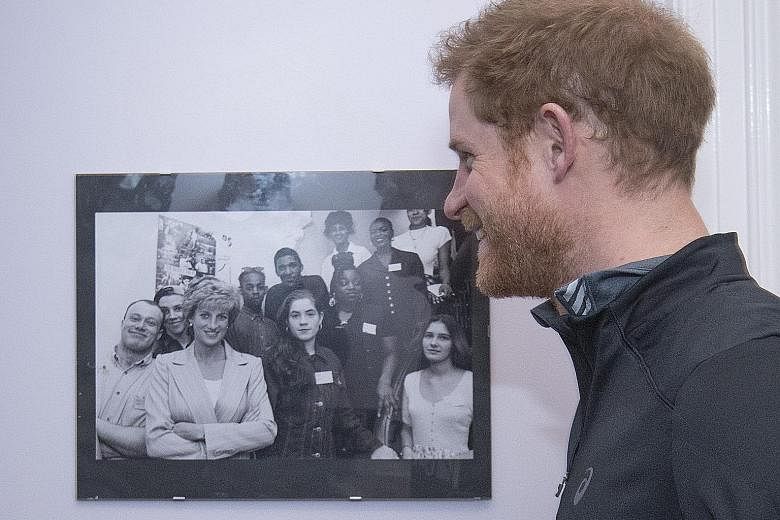 Prince Harry with a photo of his mother, Princess Diana, posing with staff and service users of The Running Charity.