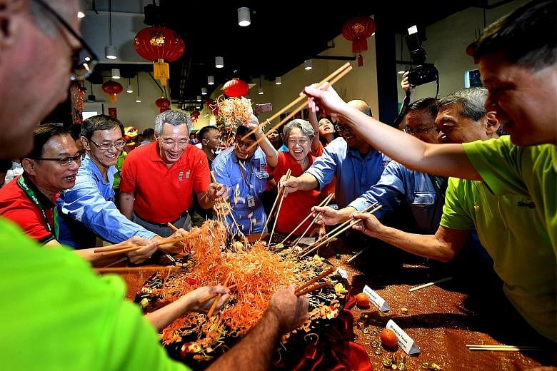 Mr and Mrs Lee, with Mr Chan (far right) and union leaders, tossing yu sheng with workers on duty at Senoko Power Station on Saturday, the first day of Chinese New Year, as part of an annual tradition to thank workers in key services for keeping Sing