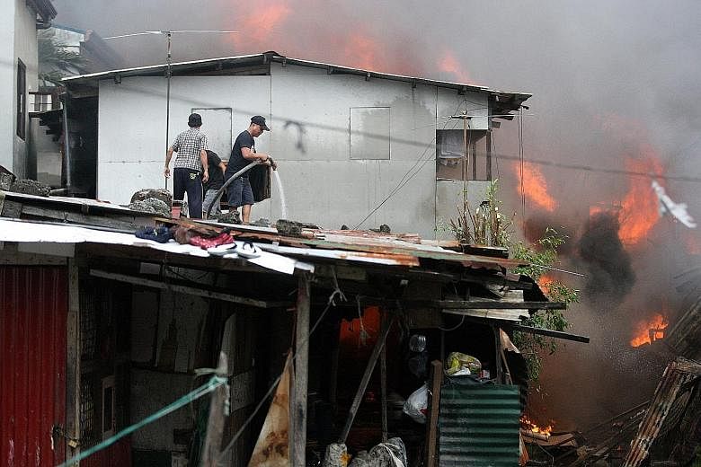 Residents trying to extinguish a fire in Las Pinas City in the Philippines on Monday. The city's Bureau of Fire Protection said at least 100 families were displaced after the fire engulfed a shanty town.