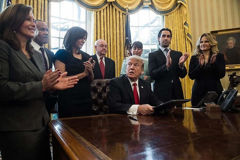 Mr Trump with small business leaders in the Oval Office after signing an executive order on Monday. His temporary ban on refugees and travellers from seven countries is facing legal challenges.