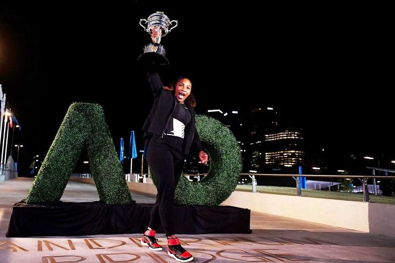 (Above) Serena Williams posing with her Australian Open trophy last Saturday after defeating her sister Venus to overtake Steffi Graf's Open-era record of 22 crowns. 