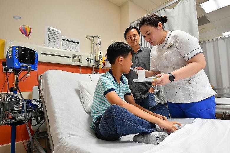 Nurse Michelle Tan showing the small dose of peanut that Shih Kai was to be fed with at NUH yesterday. His father, Mr Tng, said the boy's increased tolerance to peanuts has made a big difference to the family.