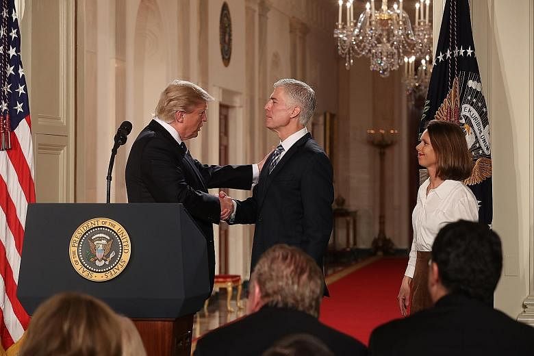 President Trump with Mr Gorsuch and his wife, Mrs Louise Gorsuch, at the White House in Washington on Tuesday. Mr Gorsuch is Mr Trump's nominee to replace the late Antonin Scalia on the Supreme Court. Regarded as a conservative, he currently serves a