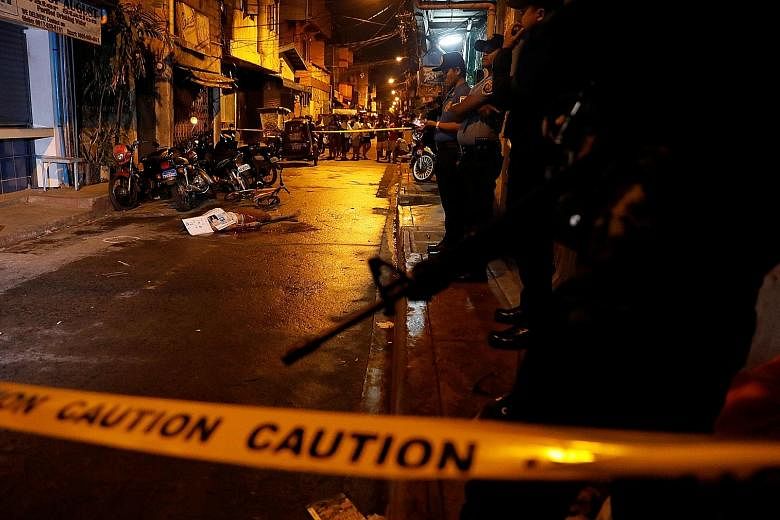 Police standing guard near the body of a man killed in what they say was a drug-related vigilante killing in Metro Manila. In a report yesterday, Amnesty International accused police in the Philippines of shooting dead defenceless people, fabricating