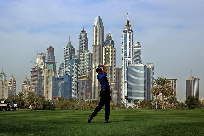 Tiger Woods playing a shot during the Dubai Desert Classic at the Emirates Golf Club. While 12 shots behind early leader Sergio Garcia, he hopes the wind blows his way for a good second round to make the cut.