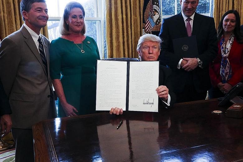 Mr Trump with a signed executive order related to the review of the Dodd-Frank Act in the White House, in Washington, DC, on Friday. The law was put in place to prevent the excessive risk-taking that led to the 2008 financial crisis.