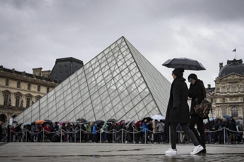Tourists queueing in the rain at the entrance of the Louvre in Paris yesterday, a day after a soldier shot an attacker at the museum.