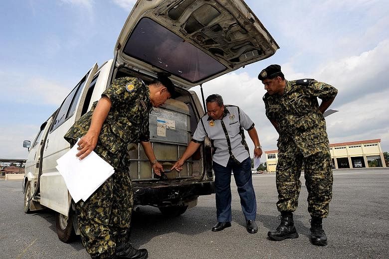 A pick-up (left) with its back seats holding a fuel tank used to smuggle petrol or diesel from Malaysia into Thailand. Malaysian border patrol (right) inspecting a van that had a tank filled with 2,000 litres of fuel to be smuggled into Thailand at B