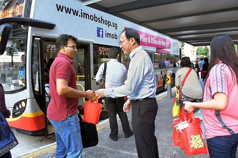 Mr Liang giving out goodie bags at the Block 458 Segar Road bus stop last Friday morning. He uses the opportunity to ask about the reliability of bus services in his ward, under an initiative called Happy Bus Stops @ Zhenghua.