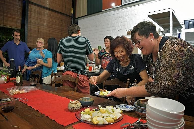 Madam Ng serving Ms Andrea Bork local food last Friday. Ms Bork, who was visiting from the United States, came to One Kind House with her mother and brother to learn how to make local dishes.