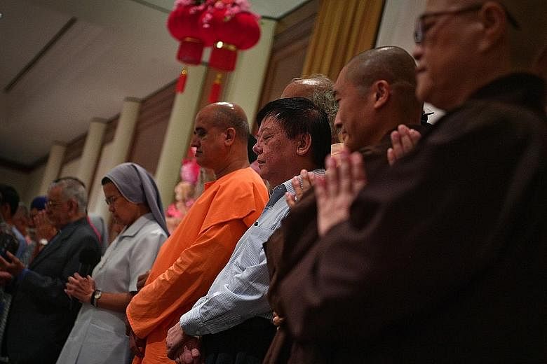 Representatives from the Inter-Religious Organisation (left) praying together at the Inter-faith Chinese New Year Reunion yesterday. The set of books (below), to be made available to religious institutions, is not for sale.