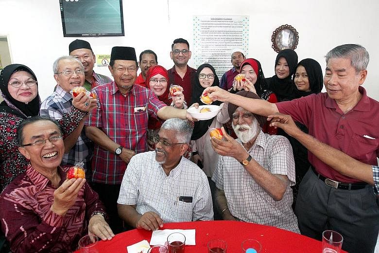 Masjid Saidina Abu Bakar As-Siddiq's chairman Ibrahim Thambychik handing out mandarin oranges in a bowl to guests at the mosque's Chinese New Year open house on Saturday. More than 400 Malaysians of various ethnicities and faiths turned up for the ev