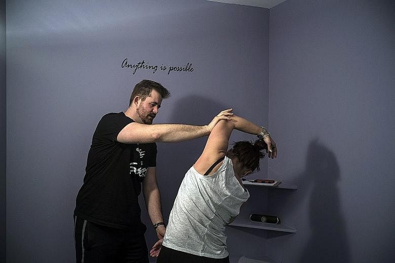 A stretch coach at Power Stretch Studios in Manhattan cupping her hand over the tight muscles on a client's shoulder blade, to compress it and help it stretch and release. Coaches help clients loosen overworked and contracted muscles (above) and also