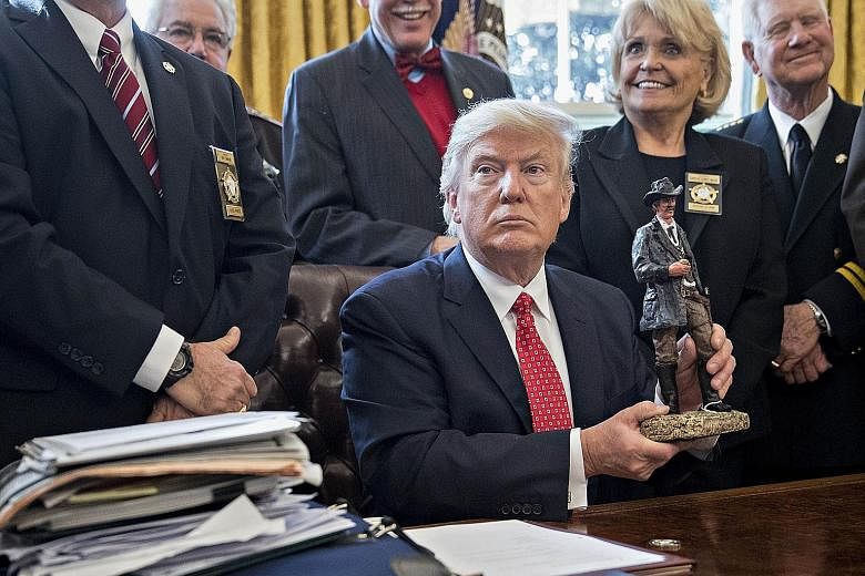 US President Donald Trump with a gift he received during a meeting with sheriffs from around the country in the White House on Tuesday. At the meeting, Mr Trump joked about destroying the career of an unnamed Texas state senator after Sheriff Harold 