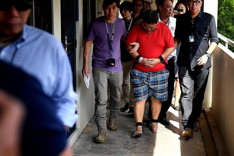 Woodlands double-murder suspect Teo Ghim Heng, 41, was escorted by police yesterday to his flat at Block 619 in Woodlands Drive 52. Teo was shackled as he was taken to the sixth-floor unit, where the bodies of his 39-year-old wife and daughter, four,