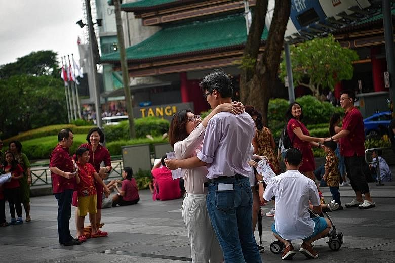 A married couple caught in an embrace during a "freeze flash mob" event in Orchard Road on World Marriage Day yesterday. To celebrate marriage in a unique way, about 350 people, including couples and families with children, gathered outside Ion Orcha