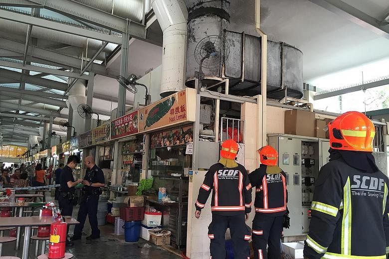 SCDF personnel at the scene of the fire in Whampoa Makan Place yesterday. Three members of the public helped to extinguish the fire, which broke out at a nasi lemak stall.