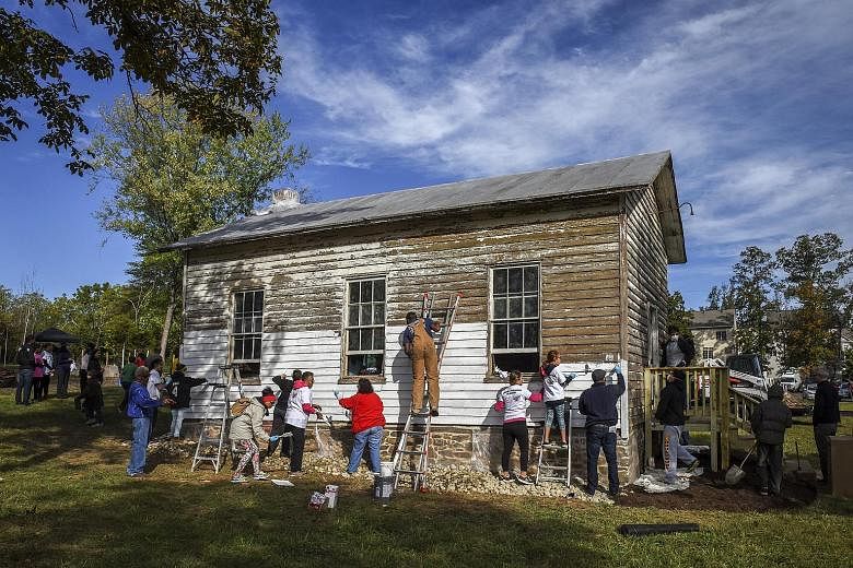 Volunteers painting the exterior of the Ashburn Coloured School in Virginia last October after five teenagers sprayed racist and anti-Semitic graffiti on it. The dilapitated, one-room 19th-century schoolhouse had been used by black children during se