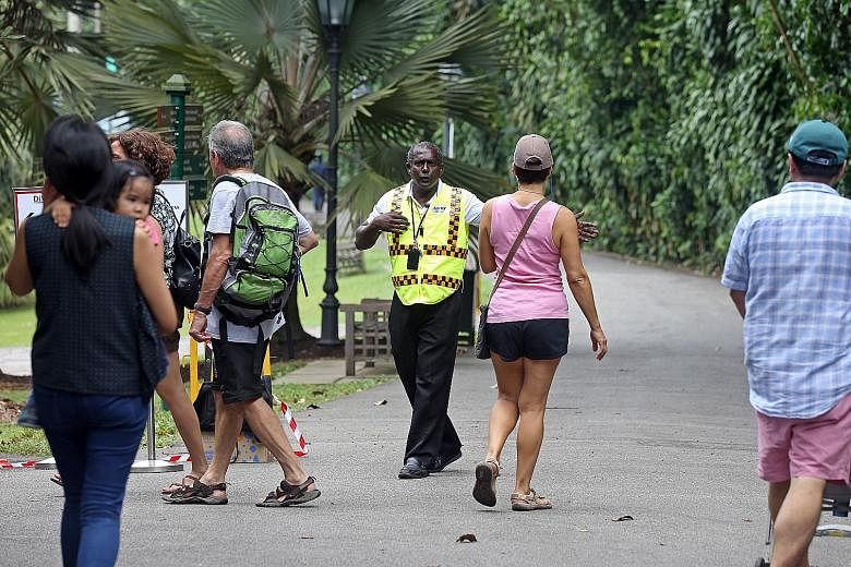 Security personnel informing visitors to the Gardens yesterday that Upper Palm Valley Road was closed as workers were still clearing the 40m-tall heritage tree that fell last Saturday.