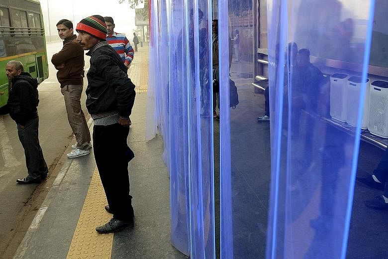 Commuters at a bus stop in New Delhi where air purifiers have been installed.