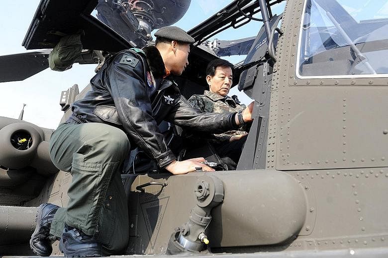 Above: South Korean Defence Minister Han Min Koo (right) inspecting an Apache helicopter during a visit to the Air Operations Command in South Korea on Monday. Left: A soldier training on the launch pad of a Patriot PAC-3 advanced missile, at a unit 