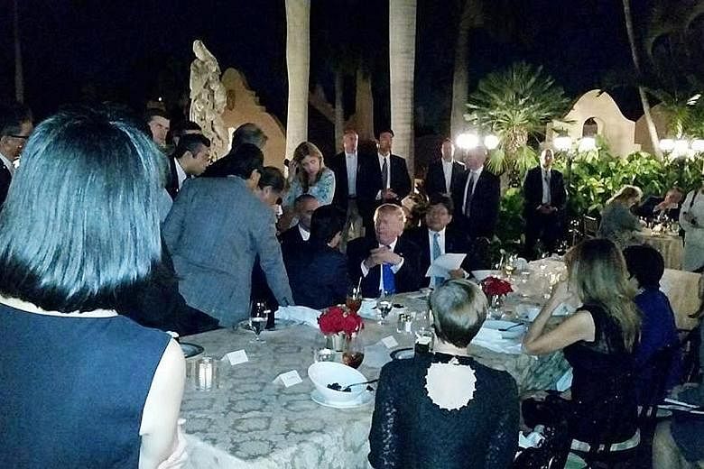 Above: Mr Trump and Mr Abe at the Mar-a-Lago club in Palm Beach, Florida, last Saturday, after North Korea's missile test. Below: Mr Abe huddling with his aides at the club. The social media posts, which said the two leaders conferred while in the pu