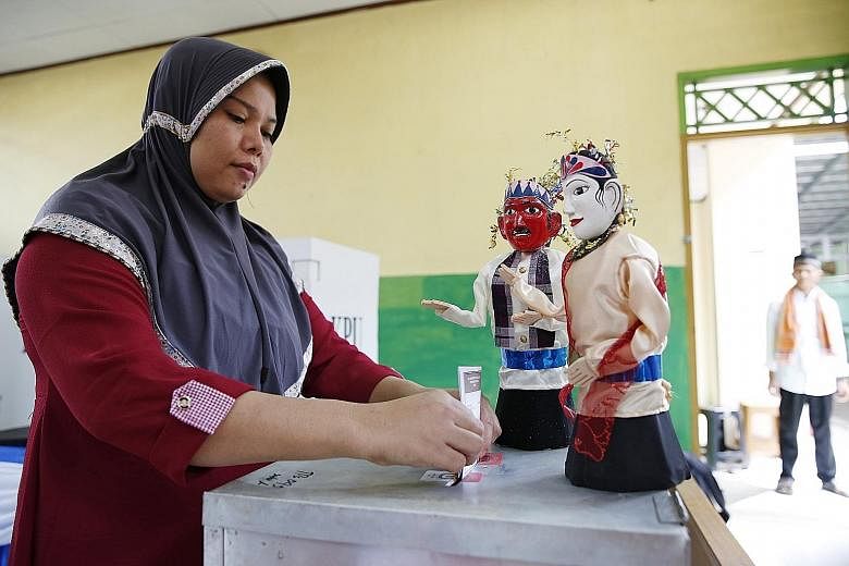 Election workers at a polling station in Jakarta. Election rules in Indonesia require candidates to win a majority of the vote, but exit polls in the Jakarta governor race point to about 80 per cent of votes evenly spread between the two leading pair