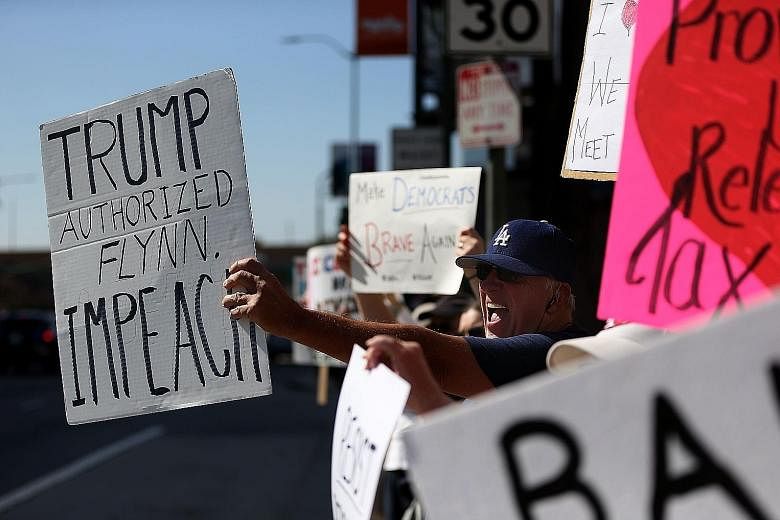 Anti-Trump demonstrators protesting in Los Angeles on Tuesday. Amid calls for an independent investigation, the White House admitted that the President was told three weeks ago that Mr Flynn may have misled colleagues about his Kremlin contacts.