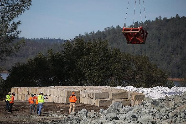 Workers at a staging area near the Oroville Dam watching a helicopter pick up rocks on Tuesday. Urgent repairs were made to reinforce the dam's emergency spillway after it was damaged by a build-up of water following heavy rains in Northern Californi