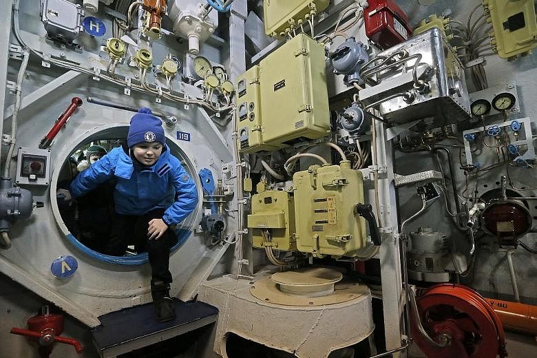 A boy climbing through the bulkhead door of a large diesel submarine as he explored the vessel during a visit by a group of children in Russia on Tuesday. The submarine- turned-museum, installed in the waters of Moscow's Khimki Reservoir, has been op