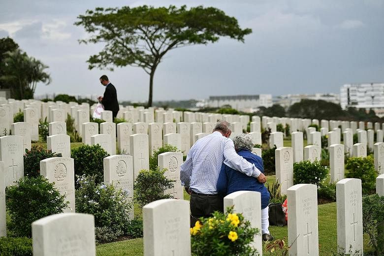 Mr Neil Munro, 67, and his wife Clare, 65, looking at the tombstone of her father's brother, after the ceremony at Kranji War Cemetery. The farmers had travelled from Australia to Singapore as part of a military history tour.