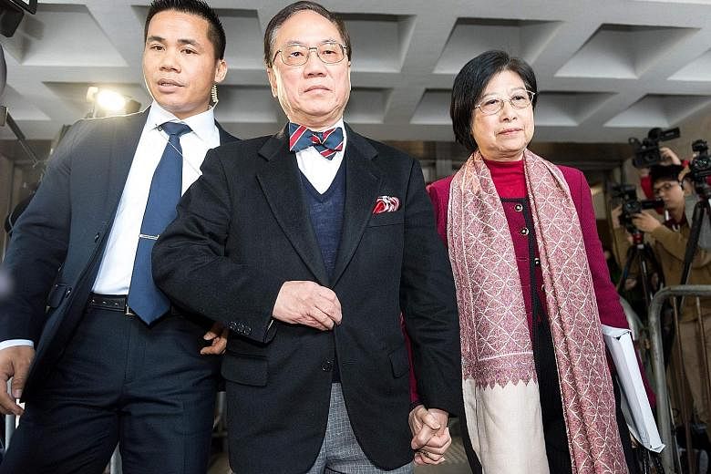 Donald Tsang (centre) leaving the High Court yesterday with his wife Selina, accompanied by a security officer. He has pleaded not guilty to three charges of misconduct and bribery.