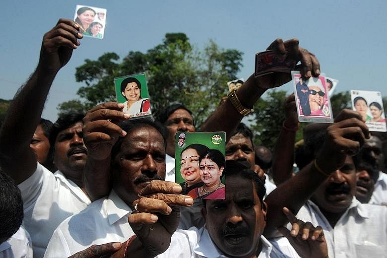 Members of AIADMK holding up portraits of Sasikala and former Tamil Nadu chief minister Jayalalithaa as they celebrated yesterday in front of the governor's residence after AIADMK legislator Edappadi K. Palaniswami was sworn in as chief minister. Mr 