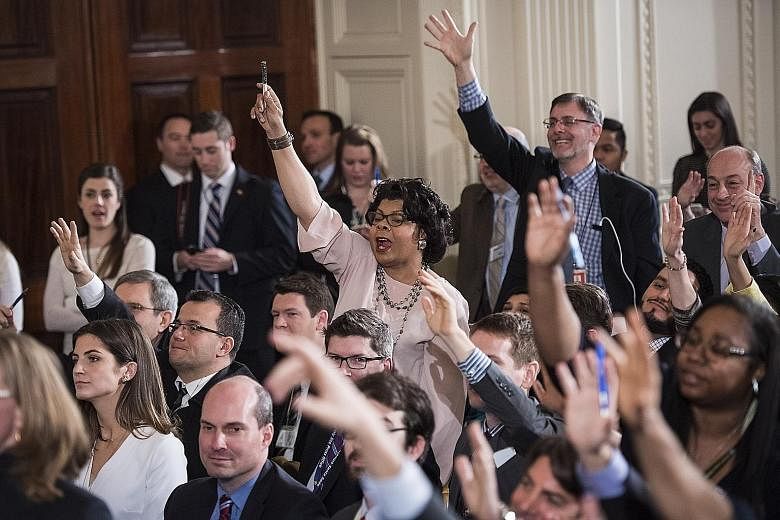 Reporters raising their hands to ask Mr Trump questions during his first solo press conference in the East Room of the White House on Thursday.
