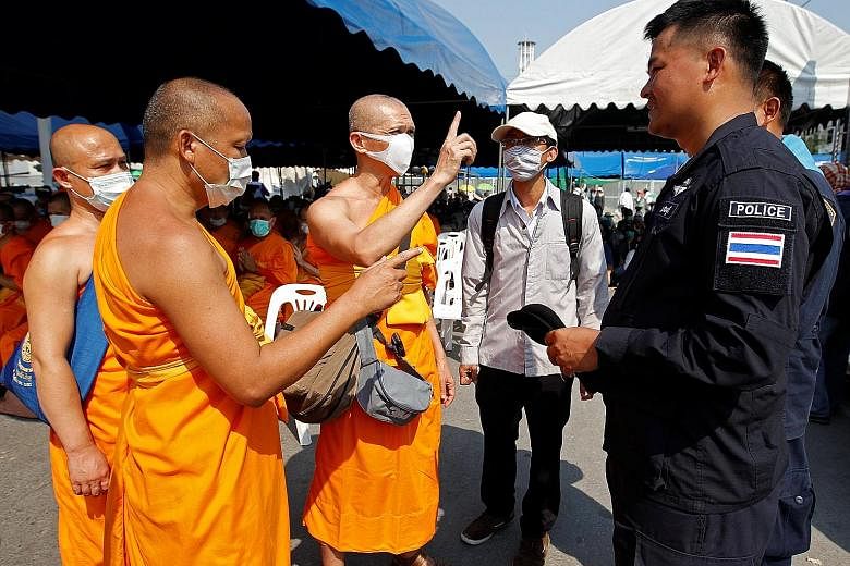 Buddhist monks speaking with policemen at the gate of Dhammakaya Temple yesterday. The temple's former abbot, Phra Dhammachayo, faces charges such as conspiracy to launder money and taking over land illegally.
