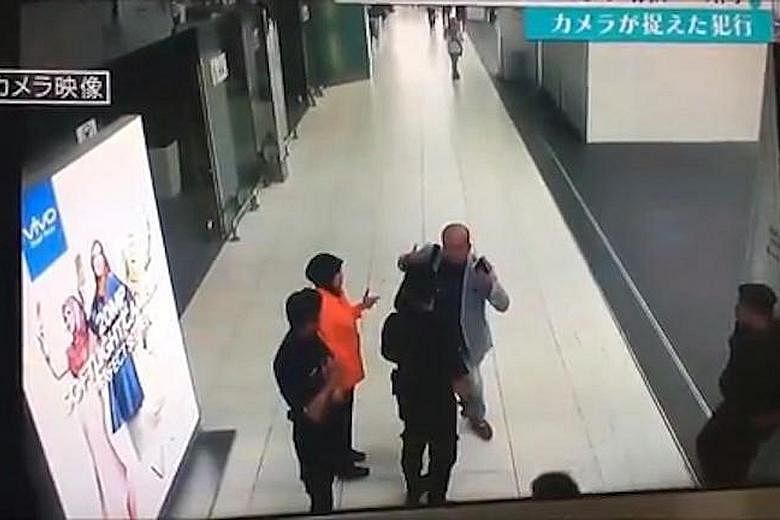 An image from CCTV camera footage showing Mr Kim (centre) checking flight schedules at Kuala Lumpur International Airport 2 on Feb 13. A woman in white is seen behind Mr Kim, throwing something over his head and locking her arms around him briefly. M