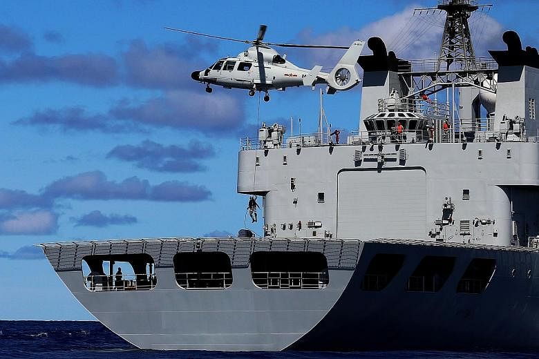 Above: Special agents trying to land on the deck of a "hijacked" ship in one of the simulated exercises conducted by China's South Sea Fleet in the eastern Indian Ocean. The flotilla of warships, consisting of guided-missile destroyers Haikou and Cha