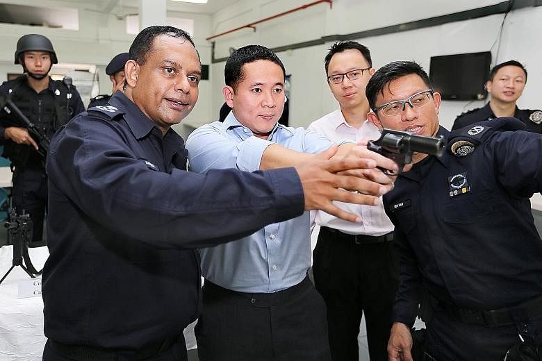 Protective Security Command commanders Manimaran Pushpanatan and Ben Tan guiding Mr Amrin Amin on the use of the Taurus revolver yesterday, with Dr Tan Wu Meng looking on. The unit was set up to protect sensitive locations and provide security at key