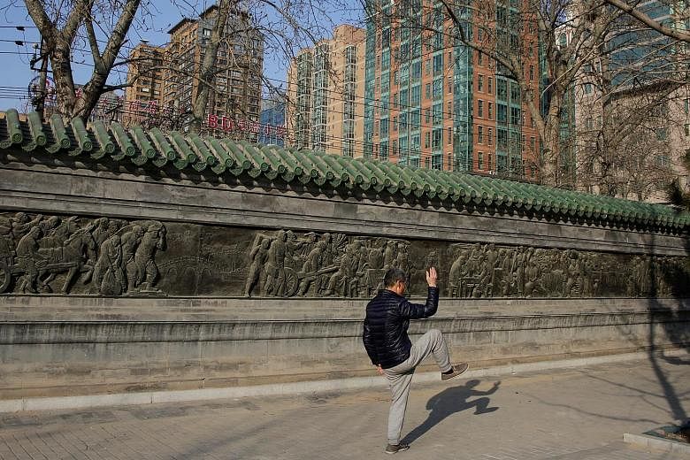 Modern apartment blocks loom as a man goes through the traditional moves of taiji in Beijing. The Chinese authorities have expanded curbs on home purchases and tightened restrictions on property lending in an attempt to avoid a housing bubble and red