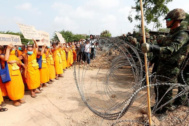 Defiant Buddhist monks stood up to a row of soldiers, with a wire barricade separating the two groups, in Pathum Thani province yesterday. Talks yesterday between officials and the Dhammakaya temple's senior monks broke down, raising the possibility 