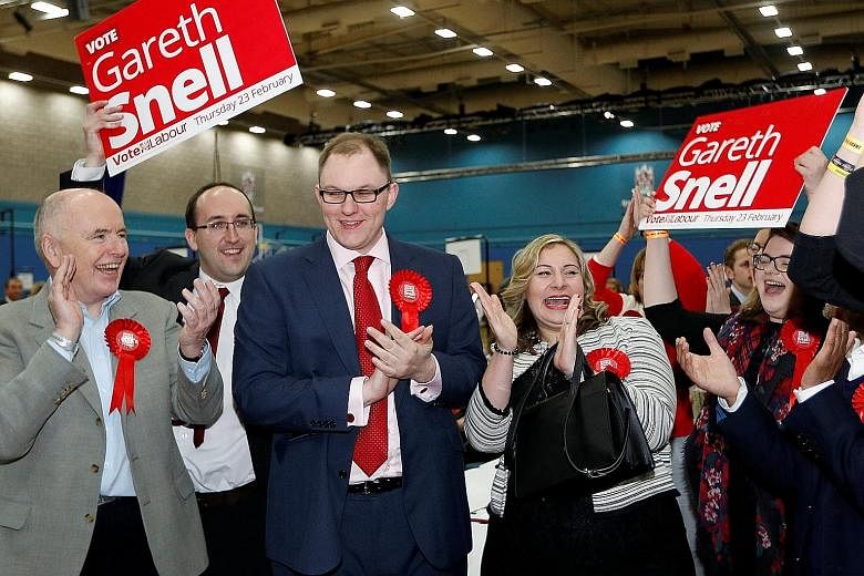 Above: Conservative candidate Trudy Harrison with her husband, Keith, after her victory in the Copeland by-election on Thursday. Right: Labour's Mr Gareth Snell (in dark suit) celebrating with his wife, Sophia, and party members after winning the Sto