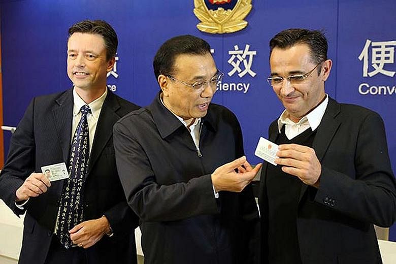 In this late 2015 photo, Chinese Premier Li Keqiang is seen with two new green-card holders. Last year, China lowered the criteria for qualification and Beijing saw a 426 per cent jump in the number of green-card applications.