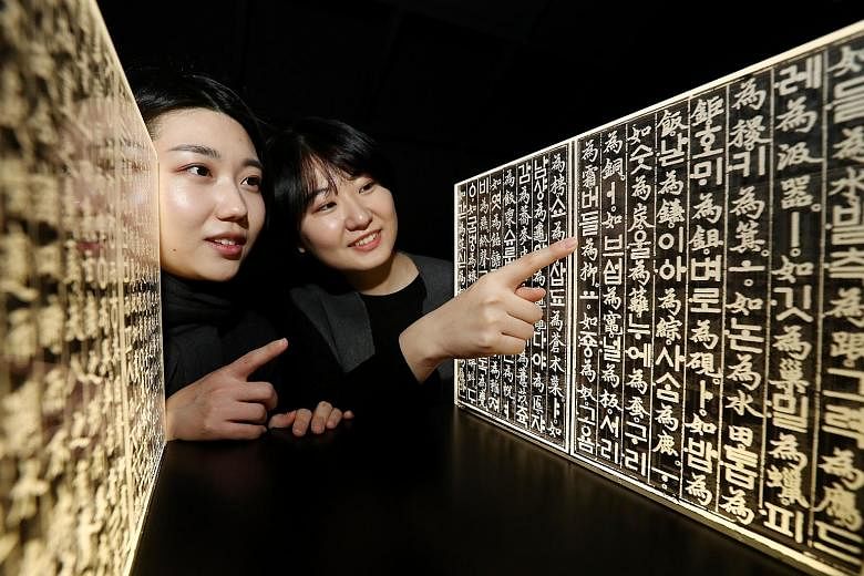 Visitors looking at acrylic panels inscribed with characters from the book Hunminjeongeum at an exhibition yesterday at the National Hangeul Museum in Seoul. The event was organised to mark the 620th anniversary of the birth of King Sejong, who inven