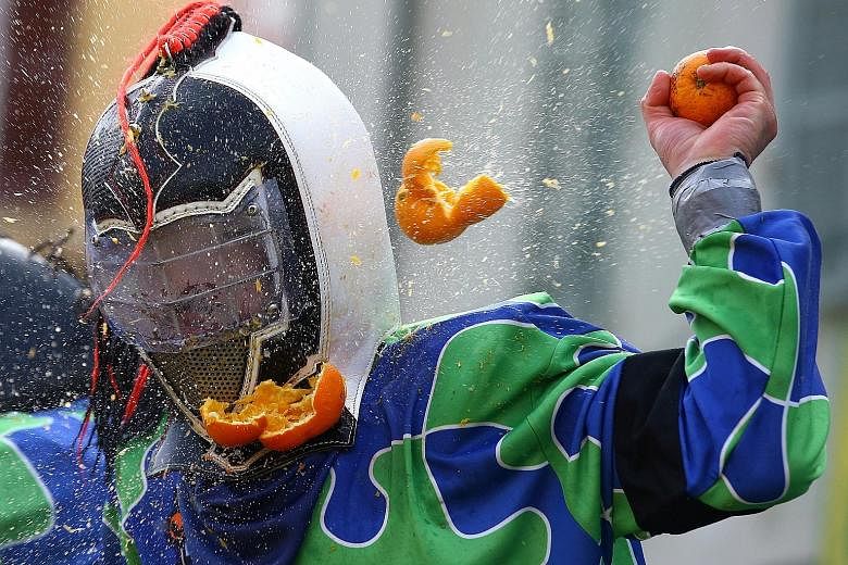 Townspeople dress up in mediaeval attire and throw oranges at the "royal guards" during an annual carnival recreating a centuries-old revolt by commoners against the monarchy in Ivrea, Italy, on Sunday.