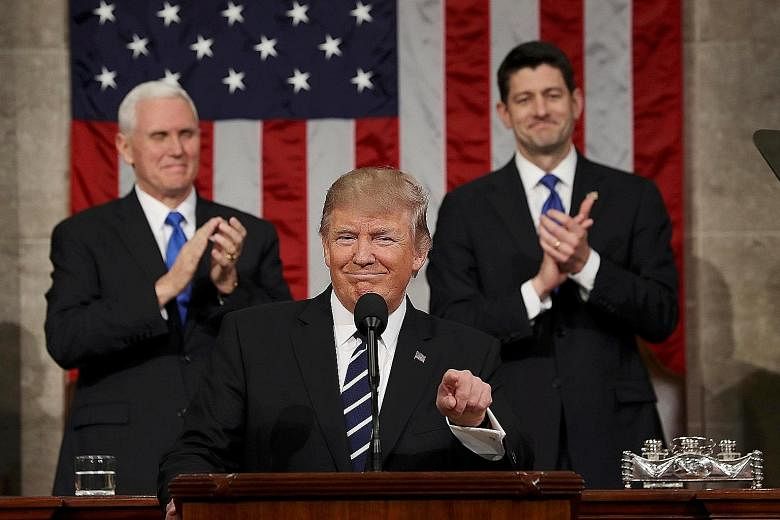 President Trump, flanked by Vice-President Mike Pence (left) and Speaker of the House Paul Ryan, preparing to address a joint session of Congress from the floor of the House of Representatives in Washington yesterday. Republicans gave him repeated st